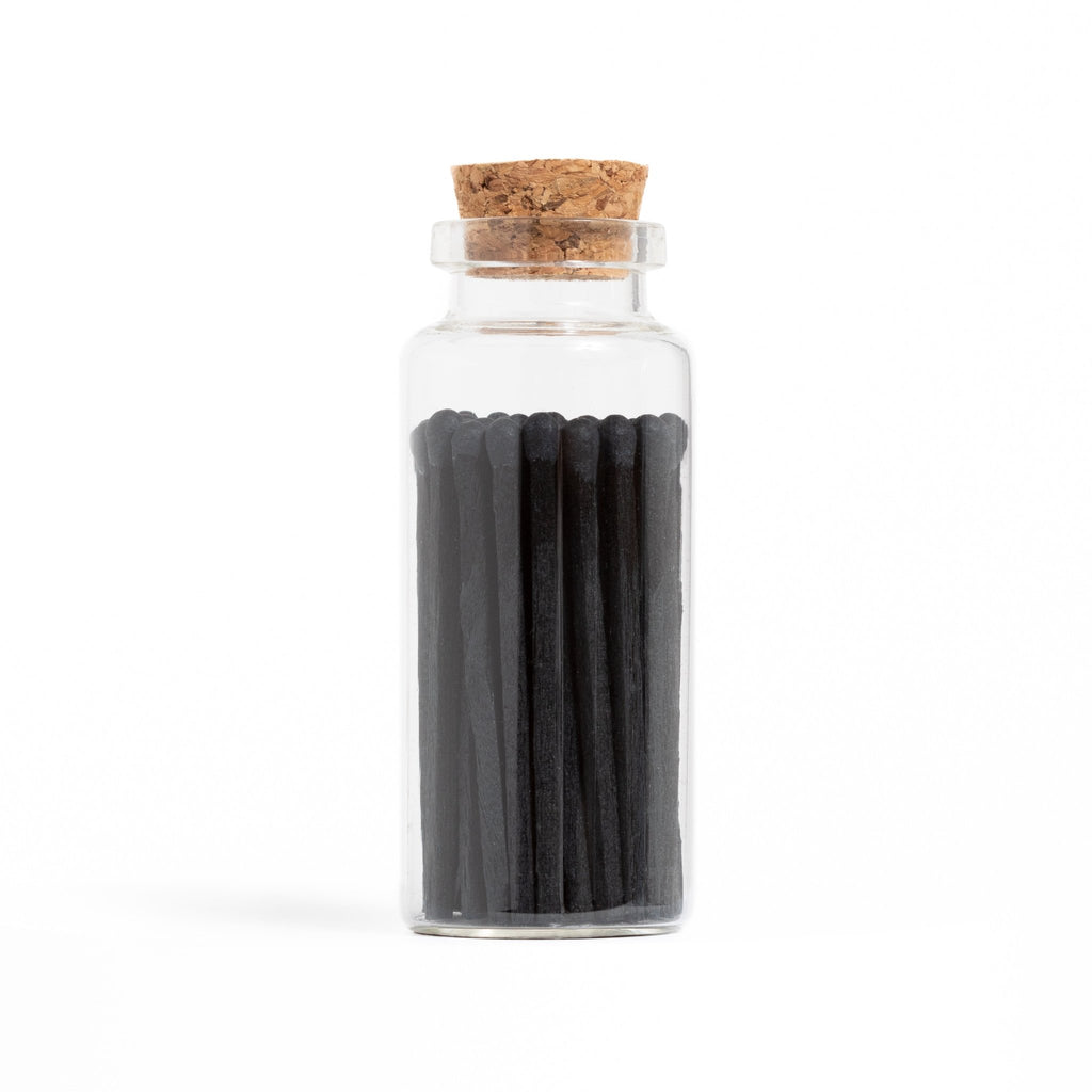 All black wood matchsticks in corked vial with match striker