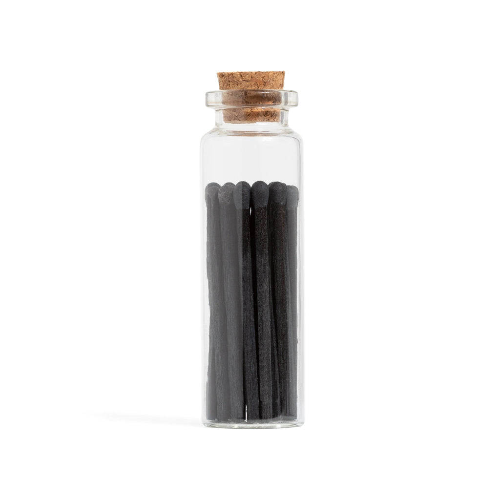 all black wood matchsticks in corked vial with match striker